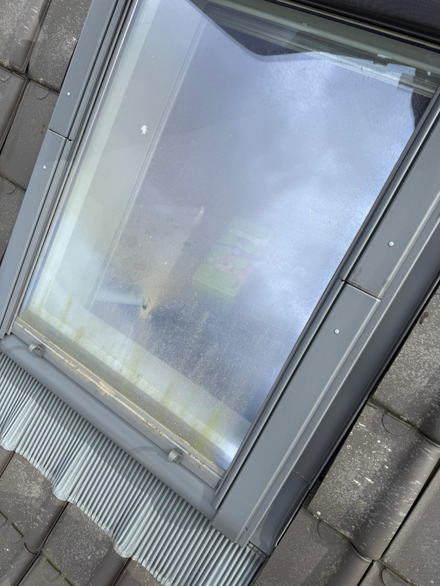 Velux-dakraam met vuil en kalksporen voor de reiniging